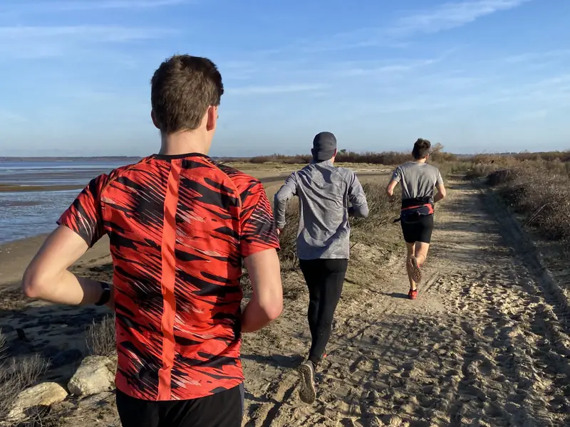 Sortie running en groupe sur un chemin de sable en bord de mer